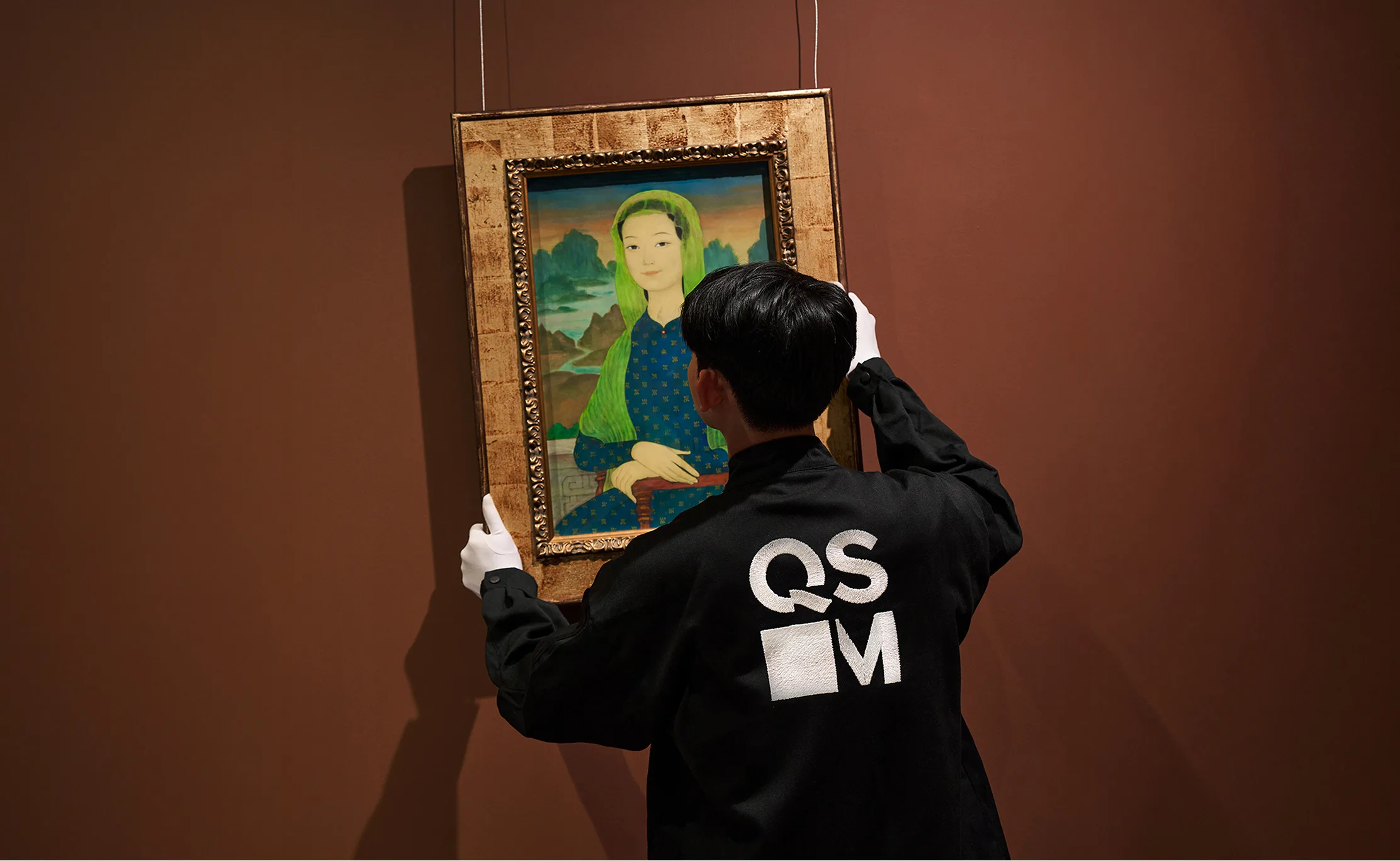 Visitor admiring classical fine art paintings hanging inside the galleries of QSAM.