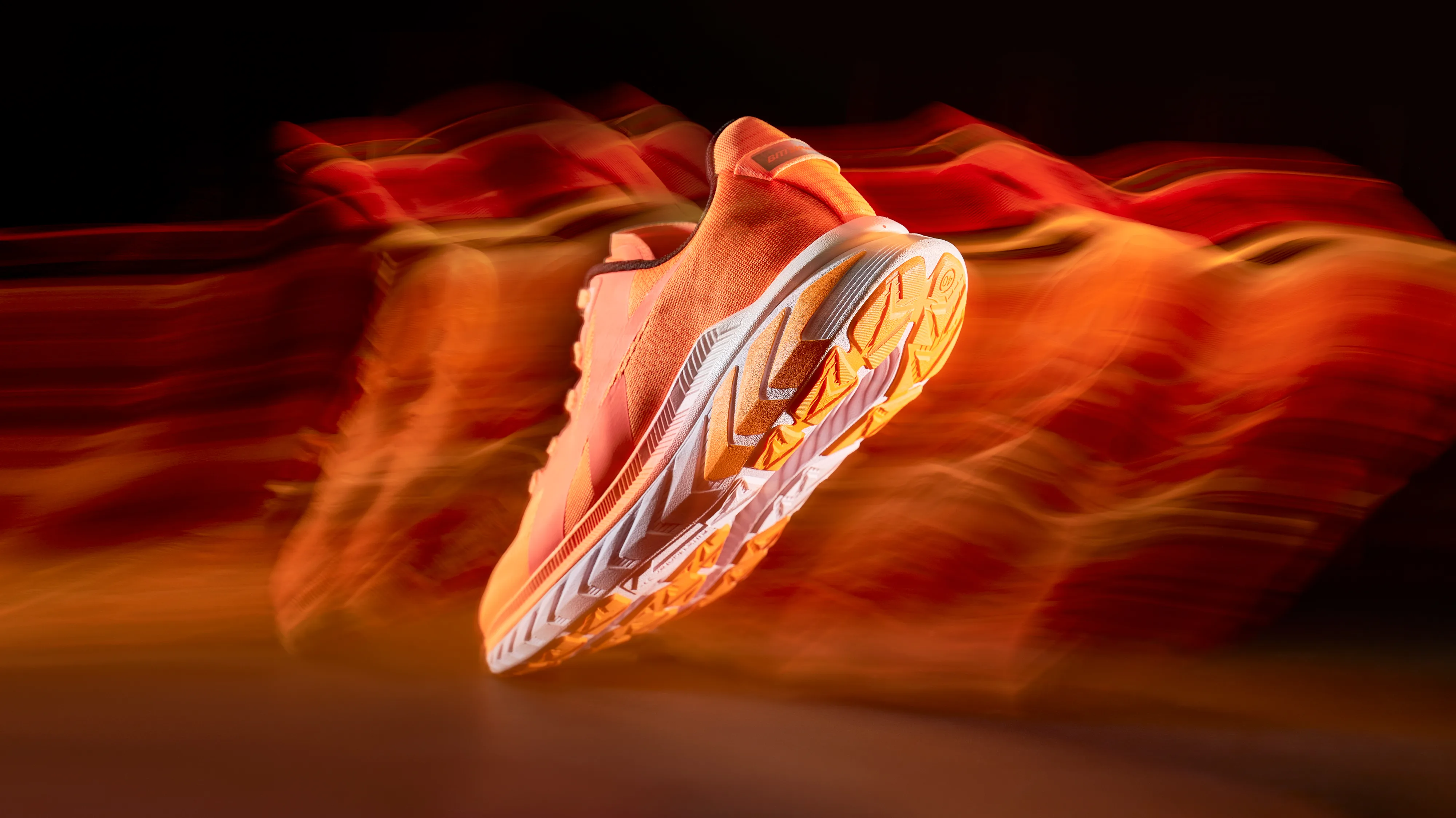 Dynamic action shot of an orange Biti's Hunter sneaker suspended in motion against a fiery abstract background.